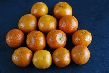 Unpeeled mandarins on a dark background with hard light.