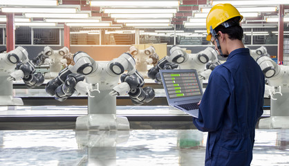 Industry 4.0 Robot concept .Engineers use laptop computers for machine maintenance, automation...