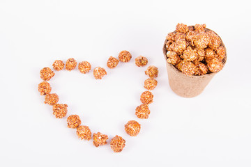 Caramel popcorn in a paper bucket and a heart made of popcorn. Romantic concept. copy space