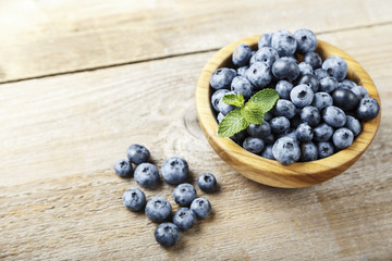 ripe organic bog whortleberry in a wooden plate on a wooden background