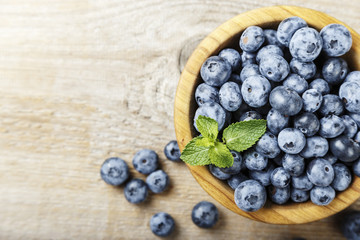 ripe organic bog whortleberry in a wooden plate on a wooden background