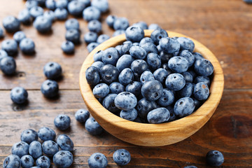 ripe organic bog whortleberry in a wooden plate on a wooden background