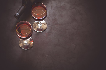 Two wineglasses with red wine and lying bottle on brown wooden desk