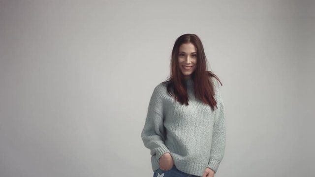 pretty young spanish woman posing in studia looking at camera and smiling wearing grey owersized sweater