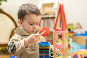 cute child playing with magnetic constructor toy