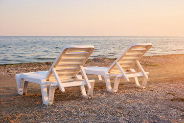 Half-turn view chaise longues on the beach. Beach chaise longues on the morning.