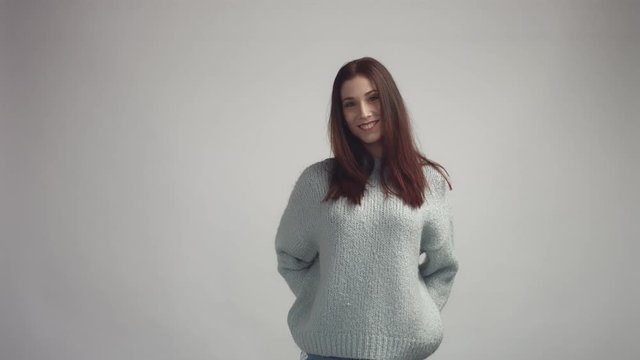 pretty young spanish woman posing in studia looking at camera and smiling wearing grey owersized sweater