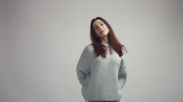 pretty young spanish woman posing in studia looking at camera and smiling wearing grey owersized sweater