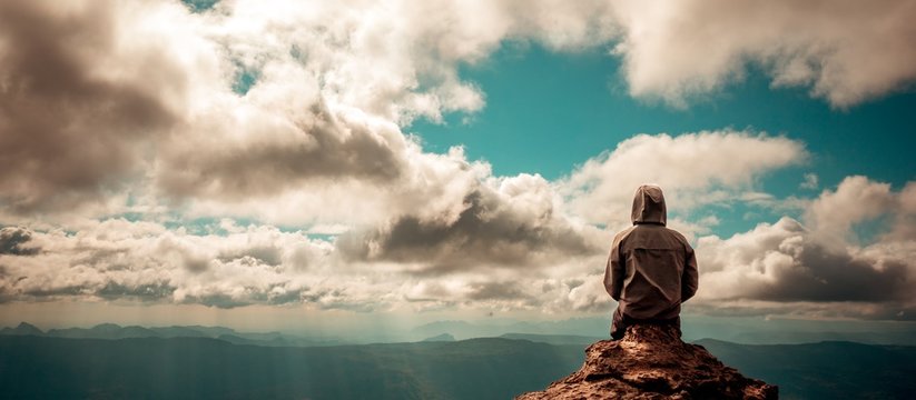 Lonely Man Sitting On Top Of Mountain Cloudy Sky