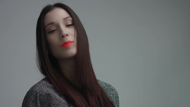 closeup of spanish woman with vivid orange matte lipstick in studio. Straight hair and ideal skin