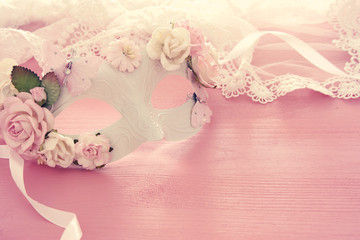 Image of delicate elegant venetian mask over wooden pink background. Selective focus.
