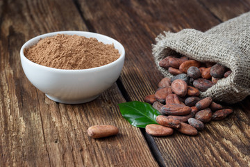 Cocoa powder and cocoa beans on wooden background