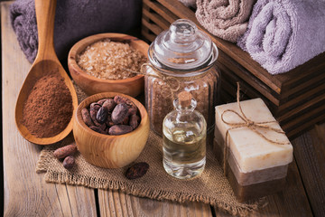 Natural cosmetic oil, sea salt and natural handmade soap with cocoa beans on rustic wooden...