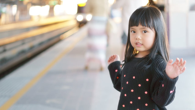 Asian children cute or kid girl waiting sky train on railway station and nature sunlight in the city for travel with space