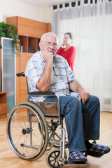 Fototapeta na wymiar elderly husband in wheelchair with sad wife
