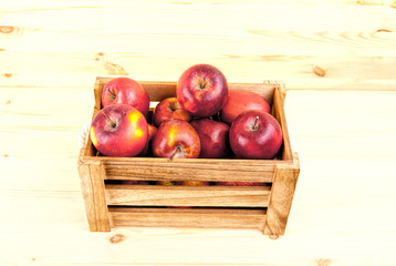 Fresh and delicious red  apples in a wooden crate on a white background .