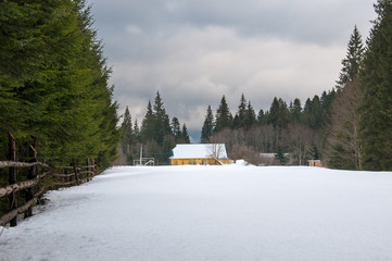 Yellow house in winter forest. Forest ranger house among deep snowdrifts in the forest.