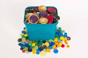 a plastic bucket with a variety of colorful buttons isolated on white background