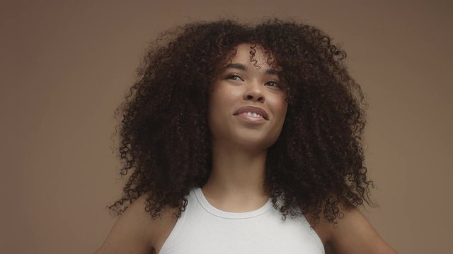 closeup slowmotion portrait of laughin black woman with curly hair in studio