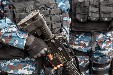 The soldier in green or blue camouflage uniform is holding M16 machine gun during his working.