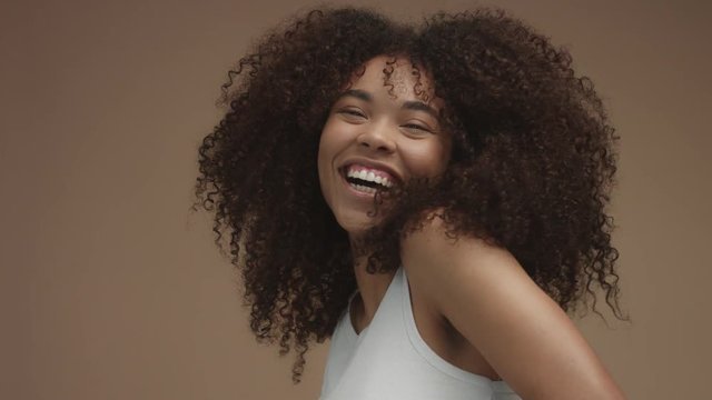 closeup slowmotion portrait of laughin black woman with curly hair in studio