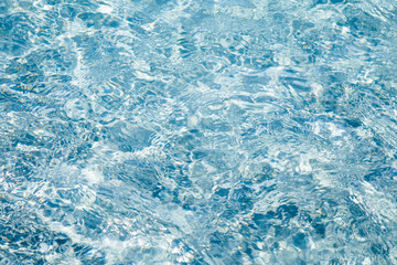 Texture of sparkling blue water. The surface is crystal clear water, beautifully iridescent in sunny day. 