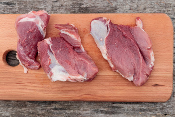 Raw pork meat on cutting board on a table. Top view