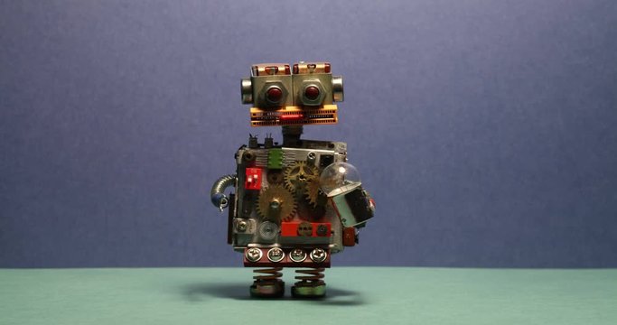 Funny robot serviceman walks and waving his arms. Toy cyborg with light bulb. Blue wall green floor background