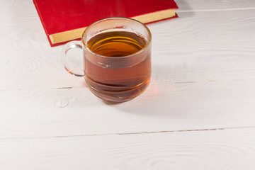 Cup of tea and book on white wooden table