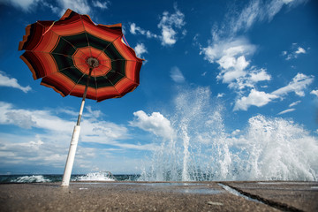 Parasol on the beach with great waves crashing on the pier