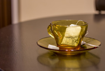 Empty cup with tea bag, spoon and sugar on table