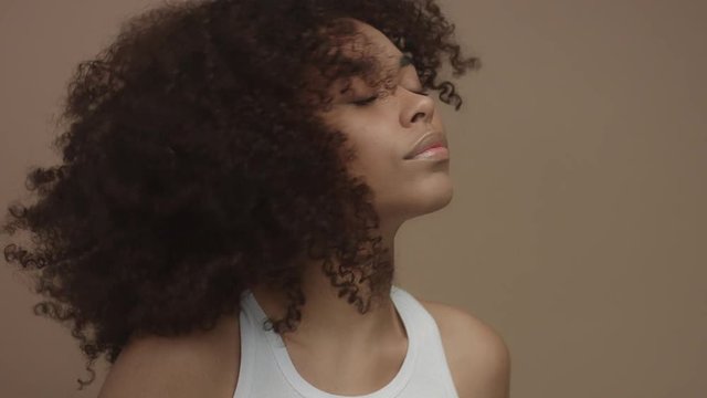 black model with huge curly hair moving shaking hair in slow motion from 60 fps studio shoot
