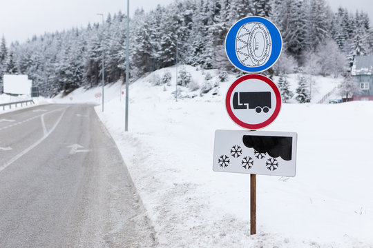 A road sign warning about the need to use snow chains and prohibiting the movement of trucks with a trailer in the snow