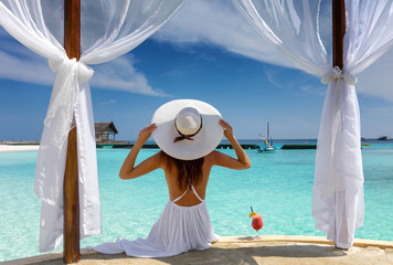 Frau mit weißem Hut genießt ihren Luxusurlaub auf den Malediven