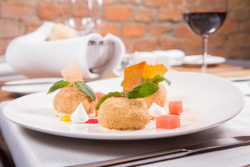 Plum dumplings with cinnamon, white chocolate and vanilla sauce served in a restaurant