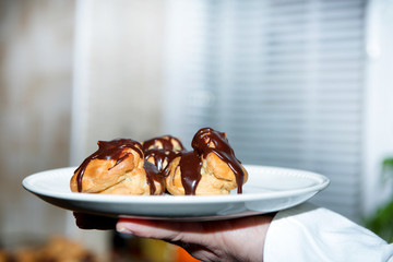 Chocolate covered vanilla cream pastry puffs close up.