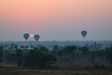 Silhouette of ancient temples and pagodas and three hot-air balloons above the ancient plain of Bagan in Myanmar (Burma) at sunrise. Copy space.