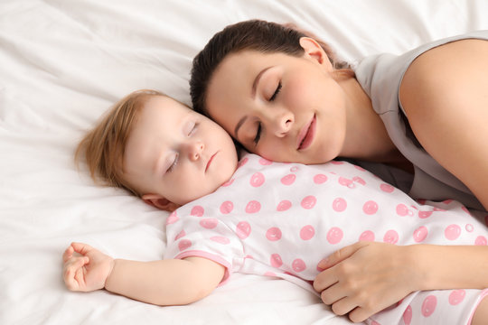 Young mother and her baby sleeping on bed