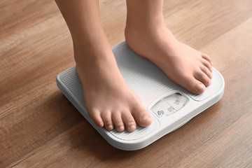 Overweight boy using scales at home