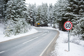 Mountain winter road with a speed limit sign