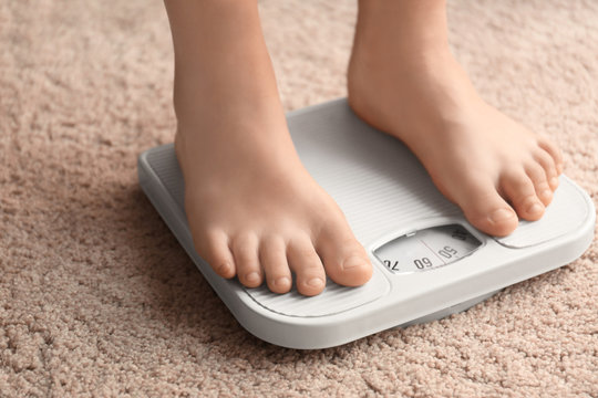 Overweight boy using scales at home