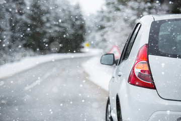 White car on a winter road through a snow covered forest. Side view