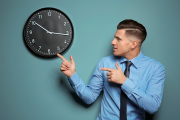 Handsome manager looking at clock hanging on wall