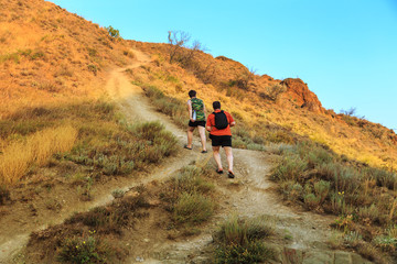 Two tourists walk across the hills.