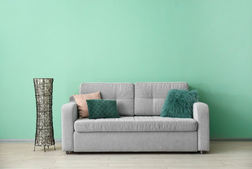 Soft sofa with pillows near color wall