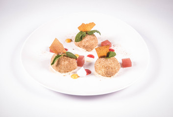 Plum dumplings with cinnamon, white chocolate and vanilla sauce on a white background