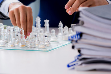 Young businessman playing glass chess in office
