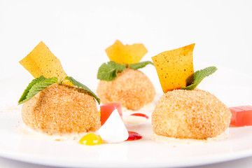 Plum dumplings with cinnamon, white chocolate and vanilla sauce on a white background