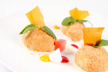 Plum dumplings with cinnamon, white chocolate and vanilla sauce on a white background