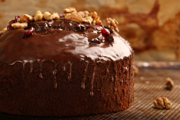 Dark chocolate cake with walnuts on on baking sheet background